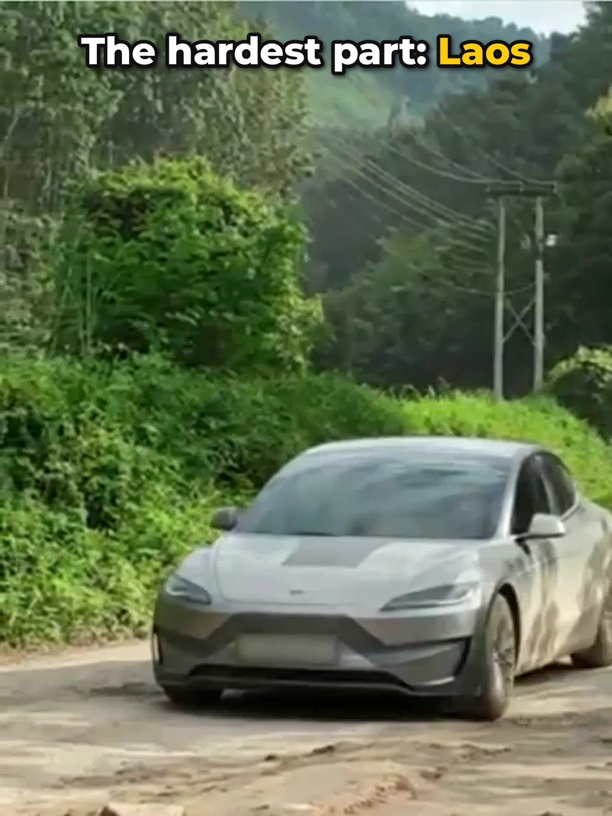 Mud-covered Tesla Model 3 on a dirt road in Laos during a drive from Malaysia to China
